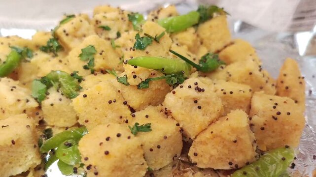 Close-up of Fresh Yellow Khaman Dhokla with Green Chili and Mustard Seeds