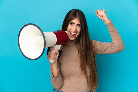 Young caucasian woman isolated on blue background shouting through a megaphone to announce something