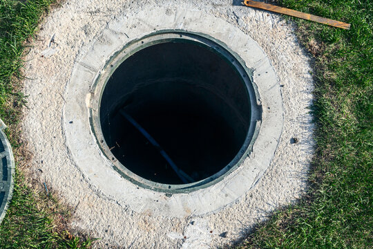 Open manhole repair process on green lawn backyard sewer line maintenance with hammer tool underground utilities infrastructure