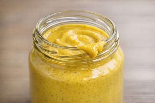 A jar of mustard with a spoon stuck in it
