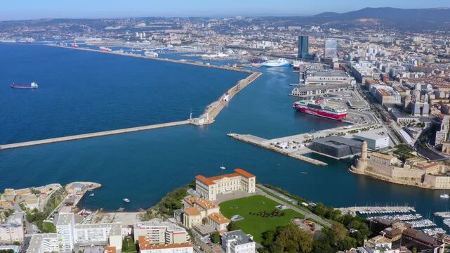 Aerial drone view of the Marseille port entrance with Corsica Linea ferry, MuCEM, Fort Saint-Jean, and Palais du Pharo gardens in Marseille, France, daytime.