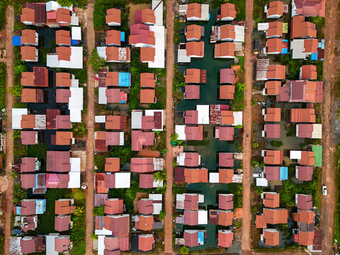 Aerial view of a village with red-roofed houses arranged along narrow canals and dirt paths in the Barito Kuala Regency, South Kalimantan, Indonesia.