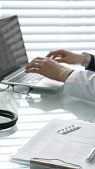 Doctor performing medical research and administrative tasks on a computer in a clinical...