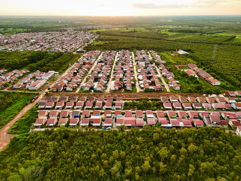 Aerial view of a residential housing development with rows of houses featuring red roofs surrounded by lush green vegetation in Barito Kuala Regency, South Kalimantan, Indonesia.