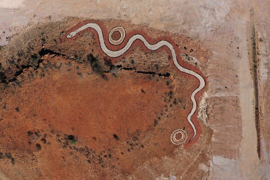 Aerial view of the Dreamtime Serpent geoglyph set within the arid red desert landscape of Birdsville, Queensland, Australia.