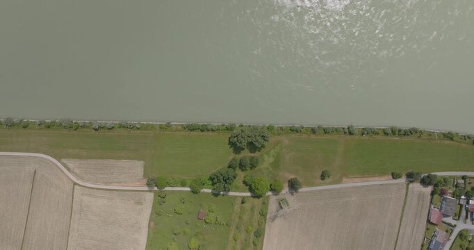 Luftaufnahme eines Baggerschiffes auf der Donau in Bayern. Drohnenaufnahme einer idyllischen Flusslandschaft mit Feldern und sommerlicher Natur.