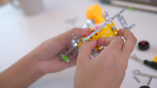 Close up of child hands assembling 3D printed robot model on table. Concept of STEM education, robotics learning, creativity, and technology development