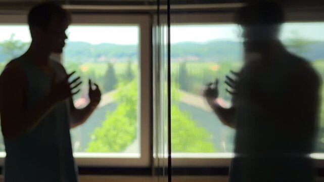 Depressed teenager in a dark room trying to discuss with his own reflection. Gesturing and giving himself a pep talk for motivation and confidence