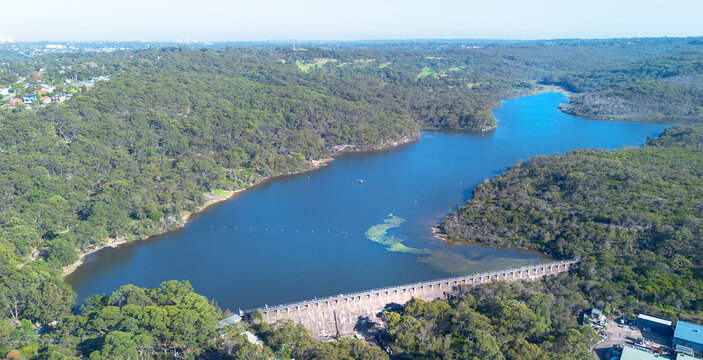 Aerial view of Manly Dam surrounded by dense native forest and vegetation with the concrete dam wall visible in Manly Vale, New South Wales, Australia.