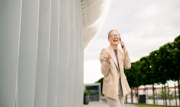Happy woman talking on the phone outside a modern building on a cloudy day