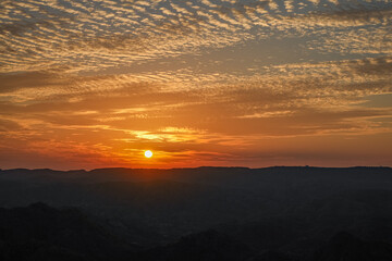 Fototapeta premium Golden sunset over mountain horizon with dramatic orange sky 
