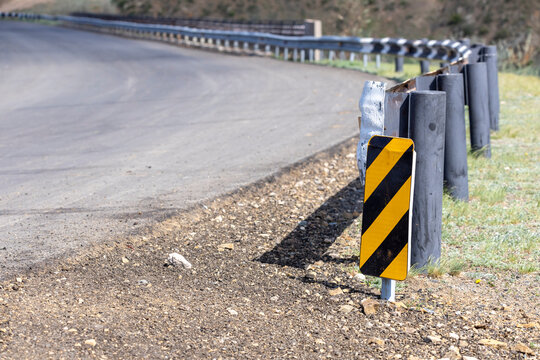 black and yellow sign on the roadside before a bend in the road
