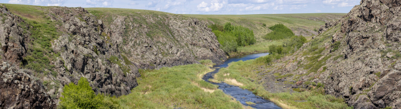 Panoramic view of a river in a rocky gorge on a sunny day.

