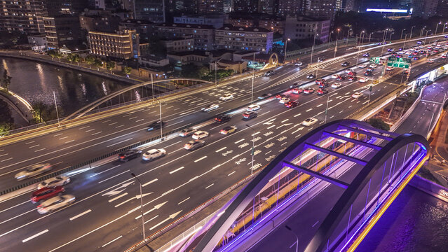 Aerial view of the illuminated Tianmu Road overpass at night with flowing traffic, modern urban infrastructure, and city lights in Shanghai, Shanghai, China.