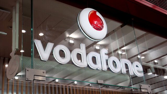 Manchester, England, UK - 18 June 2026: Vodafone store front sign, illuminated corporate brand logo on glass facade of retail shop in city centre