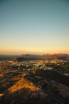 Aerial view of the holy town of Pushkar nestled among the Aravalli hills with its sacred lake reflecting the golden light of sunset in Pushkar, Rajasthan, India.