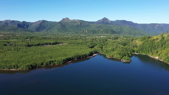 4K aerial drone footage of Coldwater Lake near Mount Saint Helens in Washington, USA. Scenic Pacific Northwest summer landscape with volcanic mountains, evergreen forest and pristine freshwater