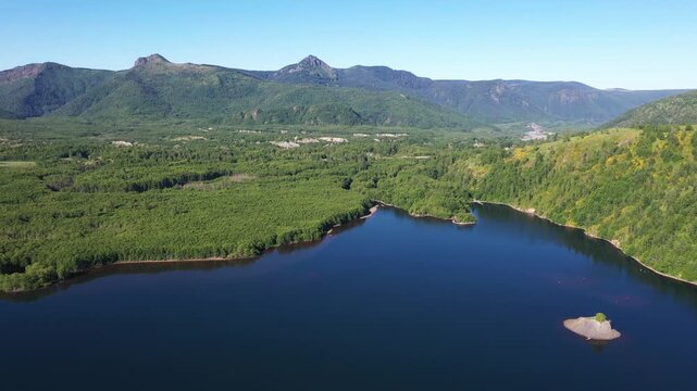 4K aerial drone footage of Coldwater Lake near Mount Saint Helens in Washington, USA. Scenic Pacific Northwest summer landscape with volcanic mountains, evergreen forest and pristine freshwater