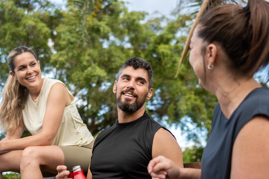Group of fitness friends talking and relaxing after outdoor workout