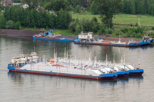 Fuel transport barge moored on a river near a cargo dock