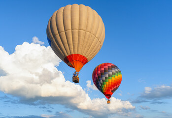 Fototapeta premium Scenic flight of hot air balloons on a clear summer day among white clouds