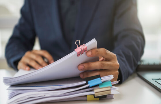 Business document organization with professional reviewing clipped paperwork and laptop to manage financial records audit compliance accounting workflow budget control and corporate productivity