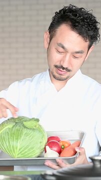 新鮮な野菜を手に料理の説明を行う料理講師を描いた縦動画、料理教室やクッキングスクール、youtubeの撮影などのイメージ