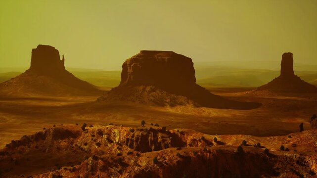 monumental desert buttes bathed in golden dusk light, warm haze, dramatic silhouettes and textured foreground, ideal for cinematic and travel narratives.