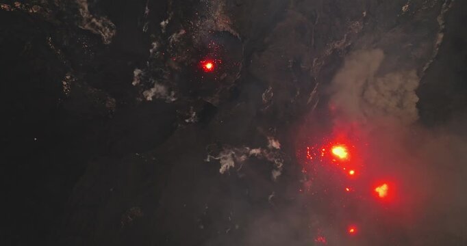 Mount Yasur volcano actively erupting lava bombs and plumes of dark smoke into the night sky, showcasing the powerful forces of nature on Tanna Island, Vanuatu. Aerial top down view
