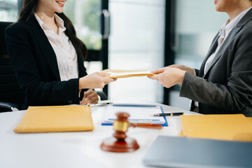 Professional lawyers hand over a contract document envelope near a judge's gavel. Legal justice,...