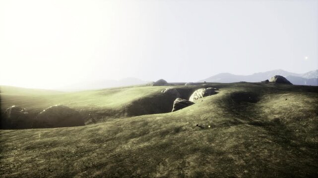 Soft backlight over misty grass slopes. Pale sky and gentle haze veil distant ridges, dewy textures on meadow, subtle glow on stones, tranquil atmosphere
