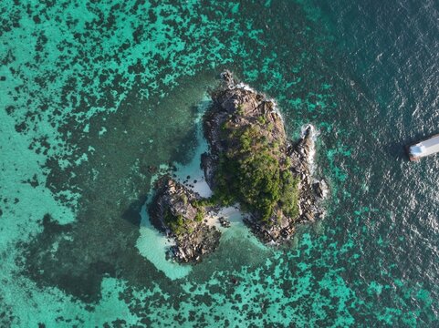Aerial view of Koh Lipe Pier and a small tropical island surrounded by vibrant turquoise coral reefs and clear shallow waters in Tambon Ko Tarutao, Chang Wat Satun, Thailand.