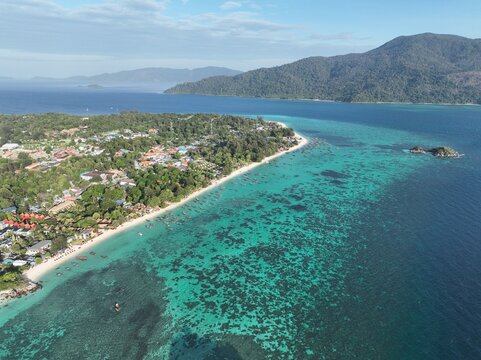Aerial view of Koh Lipe Pier surrounded by turquoise waters, coral reefs, and lush tropical vegetation on the coast of Tambon Ko Tarutao, Chang Wat Satun, Thailand.