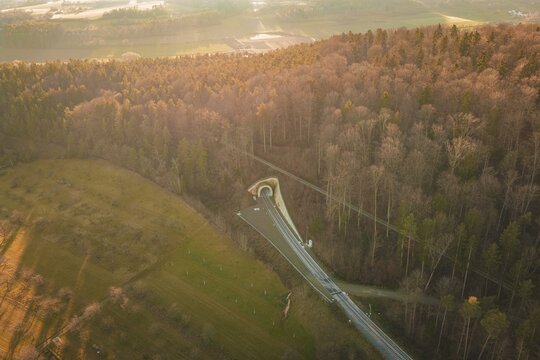 Aerial view of a wooded landscape with a winding road at sunset