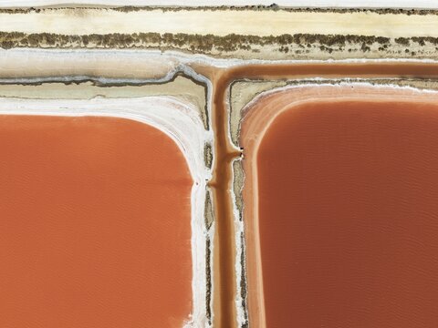 Saline ponds at the Bonanza salt works near Sanl&uacute;car de Barrameda. The reddish colour depends on the level of salinity and is directly caused by the algae Dunaliella salina and brine shrimp. Aerial view. Drone shot. C&aacute;diz province, Andalusia, Spain