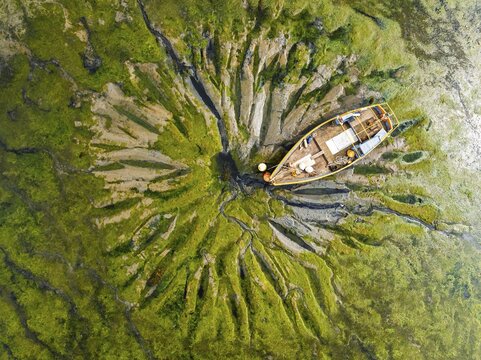 Top Down over boat and mud from drone, Paulsgrove Lake, Portchester Castle, Portchester, Fareham, Hampshire, England, United Kingdom