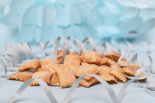 Pastries called 'Mutzen pastries or Muzenbl&auml;tter' with powdered sugar on festive blue background. Traditional German carnival and Fasching fried food