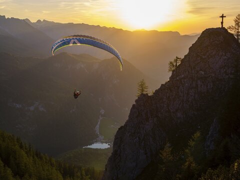 Paraglider flying next to the summit cross of the small Jenner at sunset, Reiteralpe in the background, Berchtesgaden National Park, Sch&ouml;nau am K&ouml;nigssee, Upper Bavaria, Bavaria, Germany