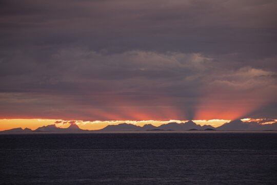 The Vestfjord in Nordland, Norway, offers a dramatic atmosphere near Bod&oslash;. Dark clouds are illuminated by the setting sun in shades of red and yellow. View towards Lofoten