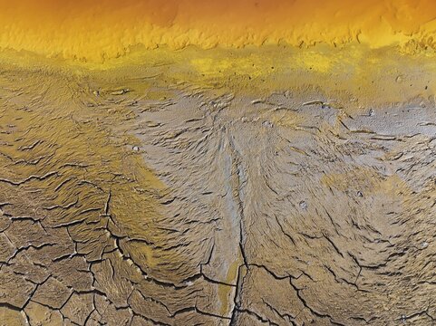 Cracked earth at the bank of the Rio Tinto (Red river) with its deep reddish hue due to oxidised iron minerals in its water, aerial view, drone shot, Huelva province, Andalusia, Spain