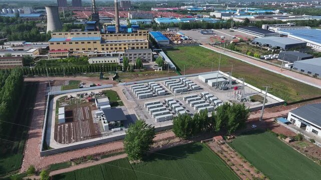 Aerial view of an energy storage power station in an industrial zone with surrounding factories and farmland