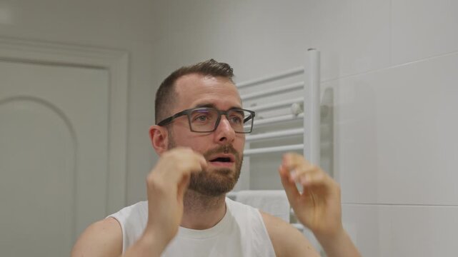 Man with poor eyesight putting on glasses in bathroom