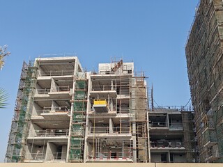 High rise under construction building with their incomplete structure. tall building with their tower crane erected beside it and having scaffolding around the building. concrete structure tower  © Usama