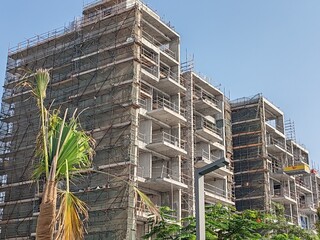 High rise under construction building with their incomplete structure. tall building with their tower crane erected beside it and having scaffolding around the building. concrete structure tower  © Usama