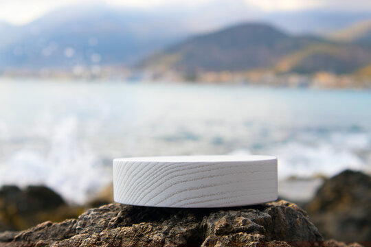 Selective focus on a white wooden platform with a defocused sea and mountains in the background. Ideal as a product background, with a lot of copy space.