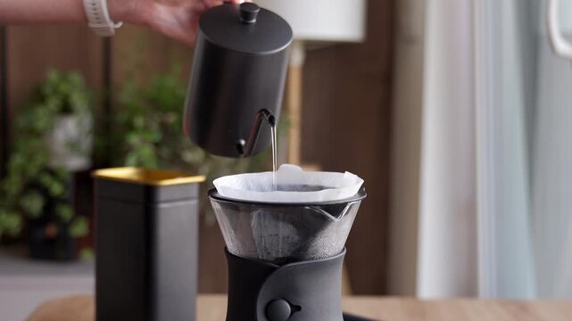 Process of drip filter coffee brewing with hot water poured over ground coffee in a paper filter. Concept of pour over coffee manual brewing and specialty coffee