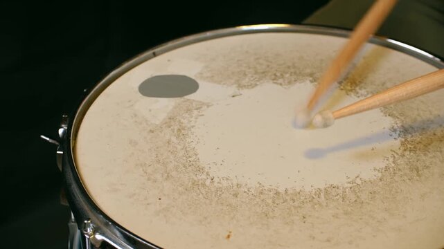 Close up drumsticks hitting snare drum head, creating powerful beat and rhythm for musical performance in professional studio with dark background. Drumsticks hitting snare drum. Training concept.