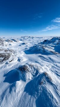 Scandinavia isolated snowfield minimalism Vast arctic tundra landscape covered in deep snow with rocky outcrops under clear bright blue winter sky