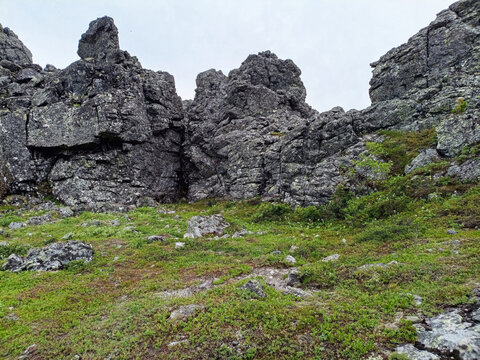 Mountain landscape with green grass, rocks and a cloudy sky.