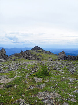 Mountain landscape with green grass and rocks under the cloudy sky.